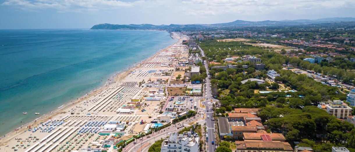 Die langen Strände von Rimini an der Adriaküste mit Reihen von Sonnenschirmen und der Stadt im Hintergrund.