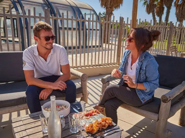 2 Personen bei einem Drink auf der Terrasse des Roan Camping Les Dunes.