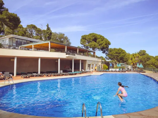 Ein Mädchen springt in den Pool des Campingplatzes Roan Internacional de Calonge.