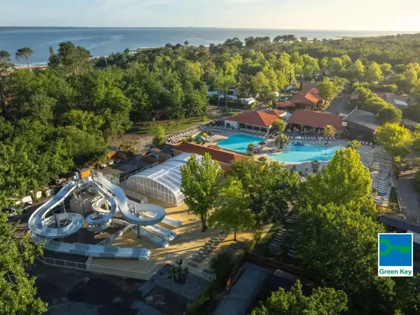 Überblick über den Pool mit Rutsche und das Meer in der Ferne auf dem Campingplatz Roan Mayotte Vacances.