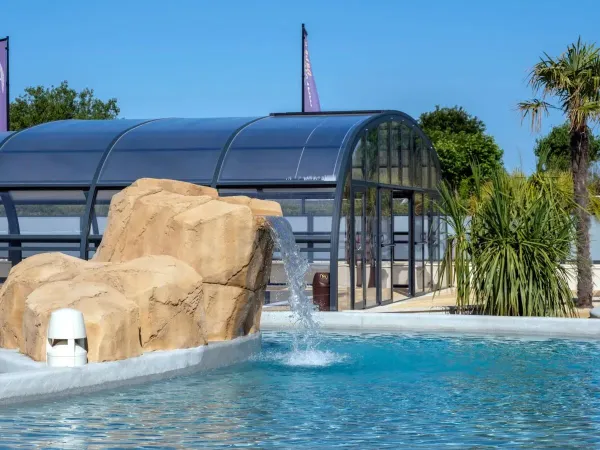 Überdachtes Schwimmbad und Freibad mit Wasserfall auf dem Campingplatz Le Domaine du Clarys in Roan.