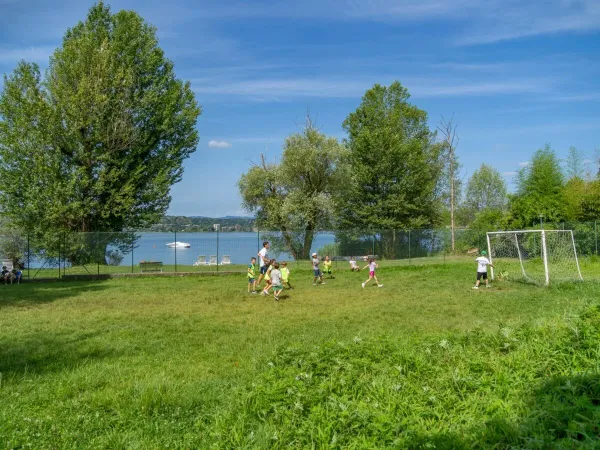 Kinder spielen Fußball auf dem Fußballplatz des Campingplatzes Okay Lido in Roan.