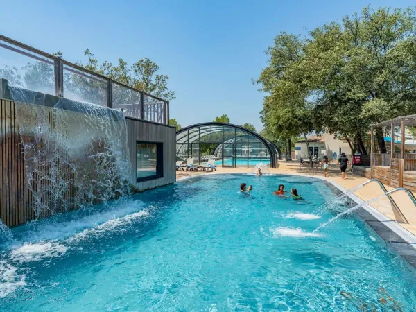 Schwimmbad mit Wasserfall und Sprinkleranlage auf dem Campingplatz Domaine de Massereau in Roan.