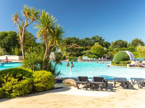 Das Schwimmbad mit Liegestühlen und der schöne Garten des Campingplatzes La Grande Métairie in Roan.