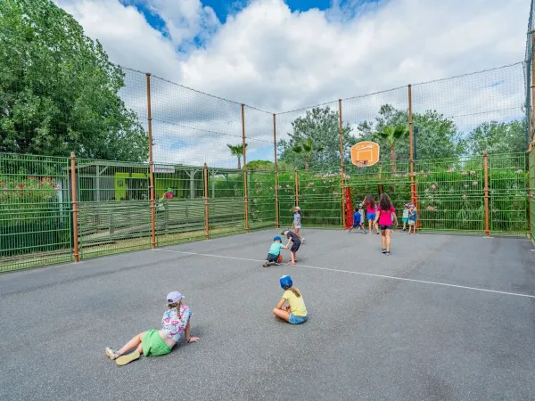 Kinder spielen auf dem Mehrzweck-Sportplatz des Roan-Campingplatzes Les Méditerranées Beach Garden.