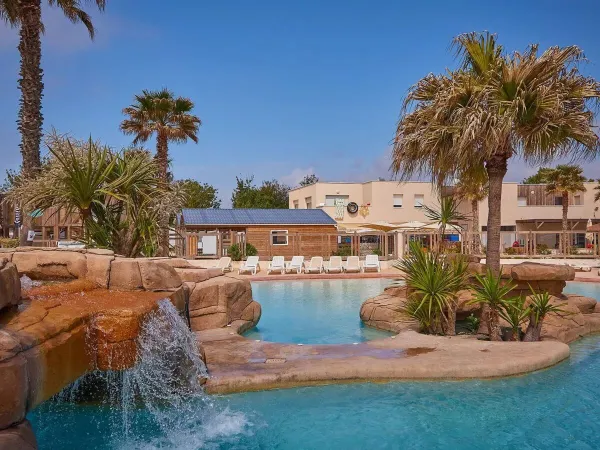 Schöne Bepflanzung am Schwimmbad mit Wasserfall auf dem Campingplatz Le Petit Mousse in Roan.