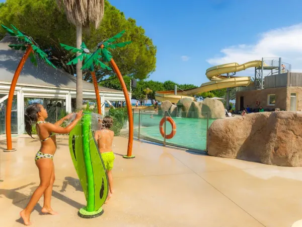 Kinder haben Spaß an den Wassersprinklern auf dem Campingplatz Arinella Bianca in Roan.