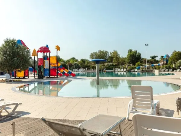 Schwimmbad mit Liegestühlen und Spielplatz auf dem Campingplatz Vigna sul Mar.