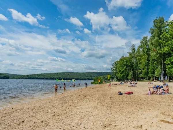 Familien sonnen sich am Strand des Sees auf dem Roan-Campingplatz Le Lac des Vieilles Forges.