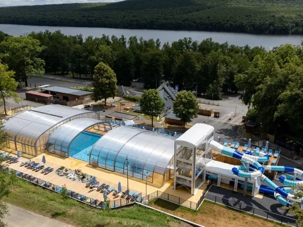 Übersicht Schwimmbad mit Rutschen und Sonnenliegen auf dem Campingplatz Roan Le Lac des Vieilles Forges.