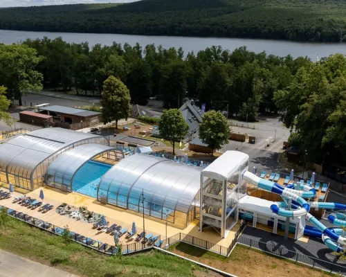 Übersicht Schwimmbad mit Rutschen und Sonnenliegen auf dem Campingplatz Roan Le Lac des Vieilles Forges.