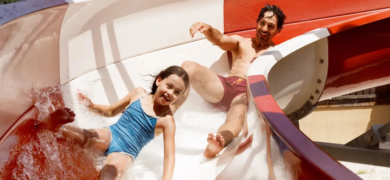 Zwei Mädchen rennen auf einem Wasserspielplatz.